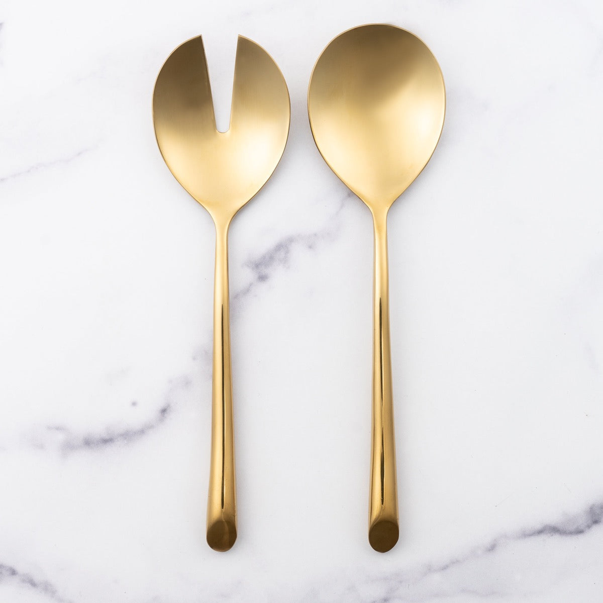 Gold fork and spoon serving set elegantly displayed, showcasing their radiant and luxurious finish.